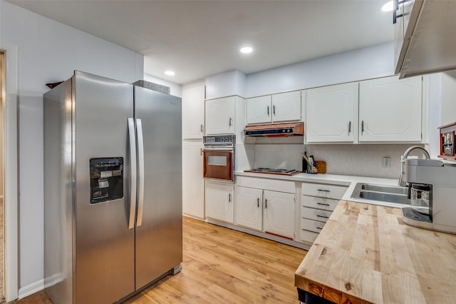 kitchen with wall oven, under cabinet range hood, white cabinets, and stainless steel refrigerator with ice dispenser