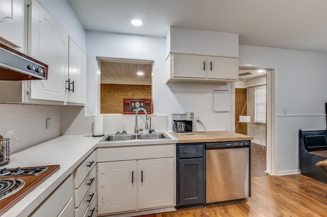 kitchen featuring tasteful backsplash, white cabinets, light wood-style flooring, stainless steel appliances, and a sink