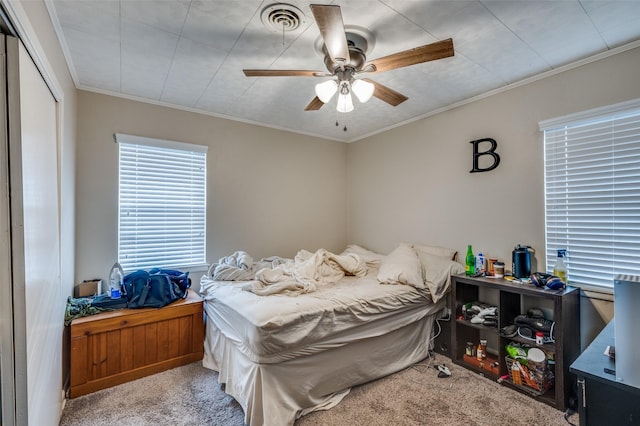 carpeted bedroom featuring a ceiling fan, visible vents, a closet, and ornamental molding