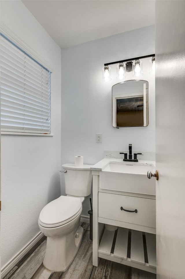 bathroom with baseboards, vanity, toilet, and wood finished floors