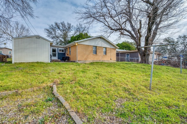 rear view of property with fence, a lawn, and brick siding