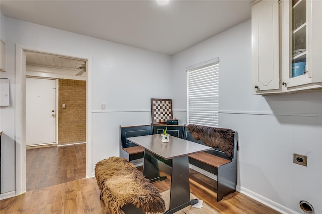 dining area featuring light wood-style floors and brick wall