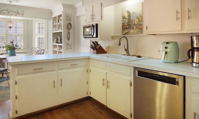 kitchen featuring light countertops, appliances with stainless steel finishes, ornamental molding, a sink, and a peninsula