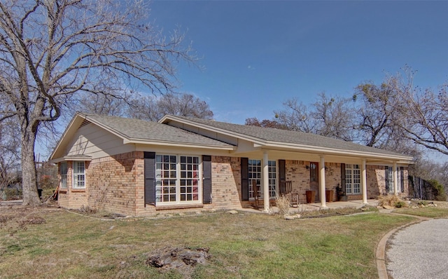 single story home with brick siding, a front yard, and a shingled roof