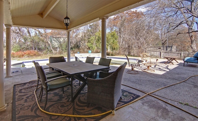 view of patio with outdoor dining space, fence, and an outdoor pool