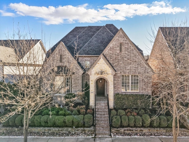 view of front of home with brick siding and a shingled roof