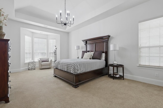 carpeted bedroom with a chandelier, multiple windows, baseboards, and a tray ceiling