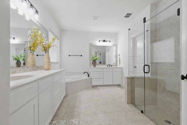 bathroom featuring visible vents, a garden tub, two vanities, a stall shower, and a sink