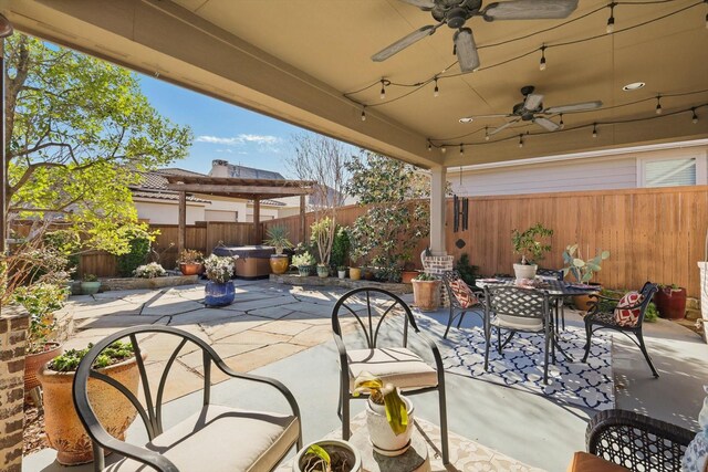 view of patio / terrace featuring outdoor dining space, a hot tub, a ceiling fan, and a fenced backyard