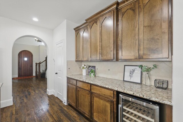 kitchen with baseboards, wine cooler, arched walkways, and dark wood-style floors