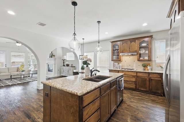 kitchen featuring visible vents, open floor plan, arched walkways, stainless steel appliances, and a sink