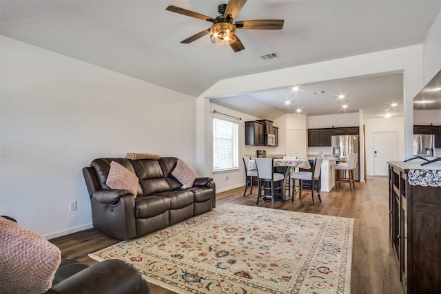 living room with visible vents, baseboards, dark wood-style floors, ceiling fan, and vaulted ceiling