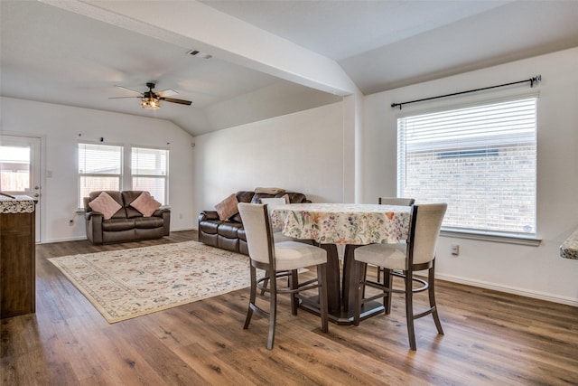 dining area with visible vents, vaulted ceiling, baseboards, and wood finished floors