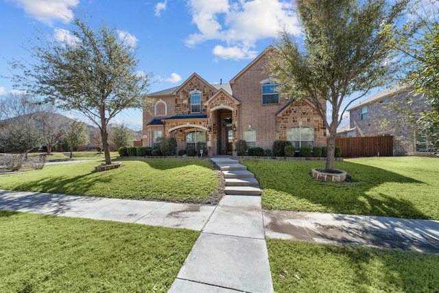 view of front facade featuring stone siding, brick siding, fence, and a front lawn