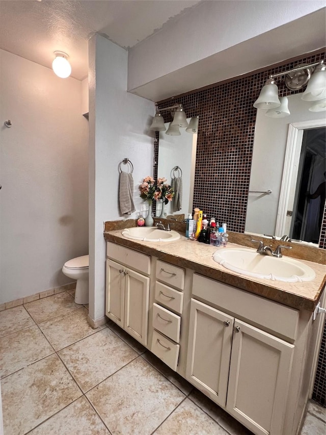 bathroom featuring double vanity, toilet, a sink, and tile patterned floors