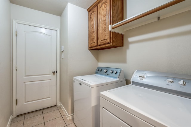 laundry area with washer and dryer, light tile patterned flooring, cabinet space, and baseboards