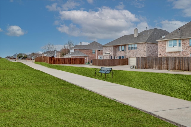 view of yard featuring a garage, a residential view, driveway, and fence