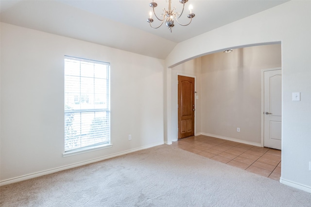 spare room featuring arched walkways, an inviting chandelier, light tile patterned floors, lofted ceiling, and light colored carpet