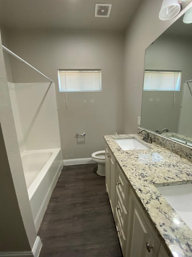 full bathroom with toilet, wood finished floors, a sink, visible vents, and baseboards