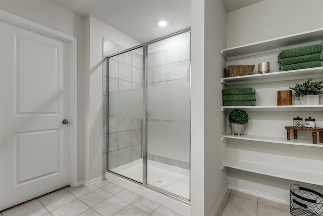 bathroom with tile patterned flooring, a shower stall, and baseboards