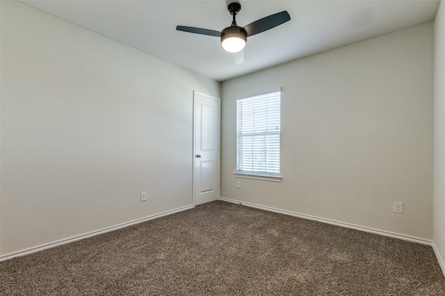 spare room with dark colored carpet, ceiling fan, and baseboards