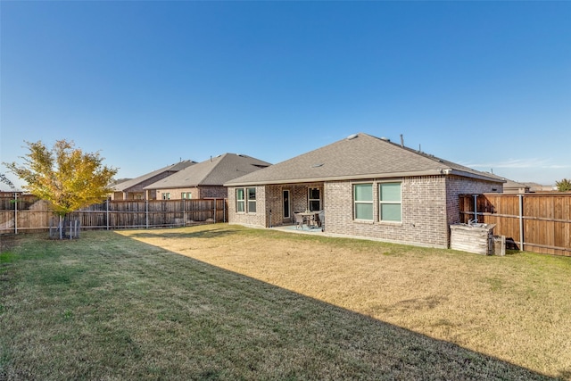 back of property with a yard, brick siding, and a fenced backyard