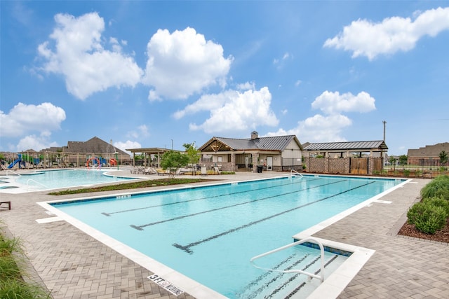 community pool with a patio area and fence