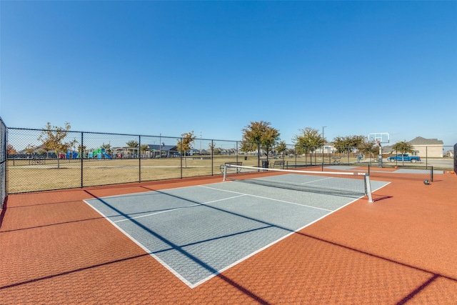 view of tennis court featuring community basketball court and fence