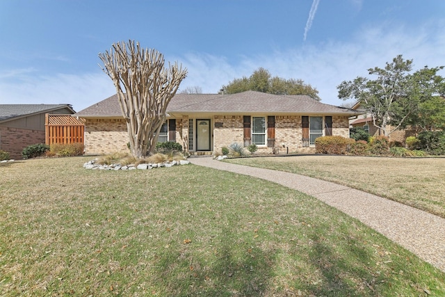 ranch-style home with a front lawn, a shingled roof, and brick siding