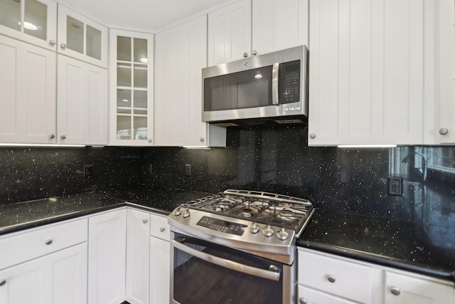 kitchen featuring appliances with stainless steel finishes, white cabinetry, glass insert cabinets, and decorative backsplash