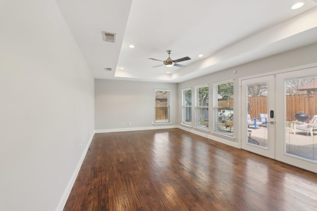 empty room featuring visible vents, baseboards, wood finished floors, a tray ceiling, and french doors