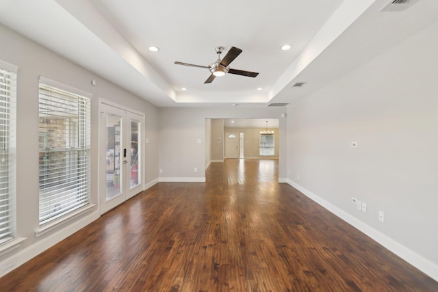 unfurnished living room featuring baseboards, a raised ceiling, wood finished floors, and french doors