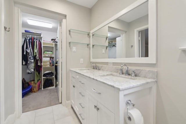 full bath with double vanity, tile patterned flooring, a sink, and a walk in closet