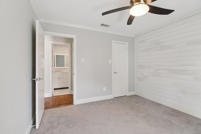 unfurnished bedroom with carpet floors, baseboards, visible vents, and ornamental molding