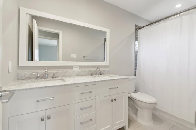 bathroom featuring toilet, tile patterned flooring, double vanity, and a sink