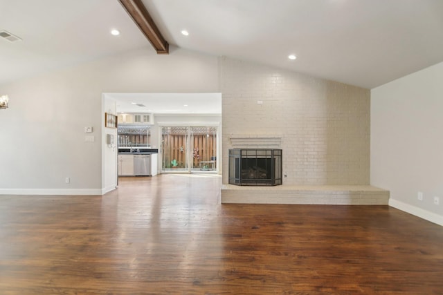 unfurnished living room with a fireplace, visible vents, lofted ceiling with beams, wood finished floors, and baseboards