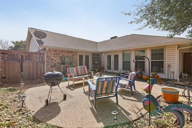 back of house featuring brick siding, fence, a patio, and french doors