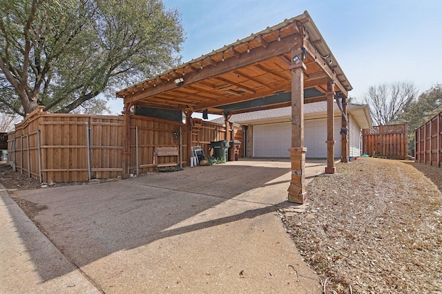 exterior space with a garage, concrete driveway, fence, and a carport