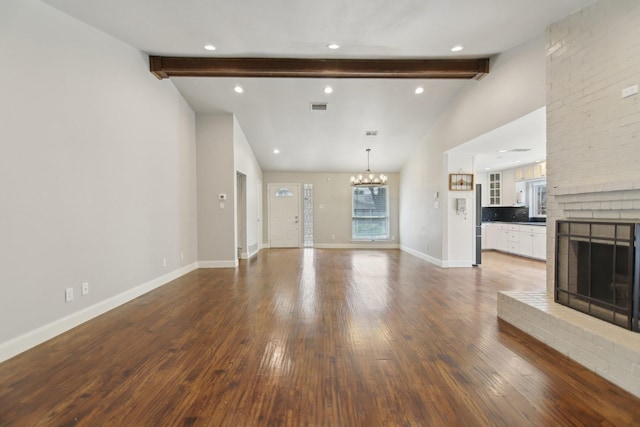 unfurnished living room with vaulted ceiling with beams, a fireplace, baseboards, dark wood-style floors, and an inviting chandelier