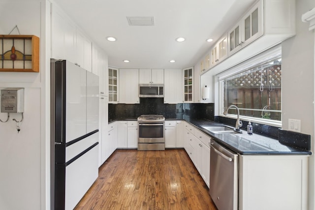 kitchen featuring stainless steel appliances, dark wood-style flooring, a sink, white cabinetry, and tasteful backsplash