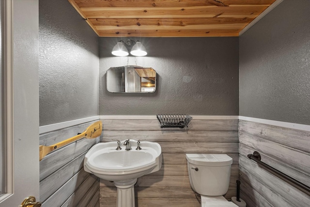 half bathroom featuring a textured wall, a sink, and toilet