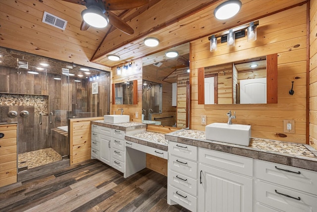 bathroom featuring lofted ceiling, visible vents, a stall shower, a sink, and wooden walls