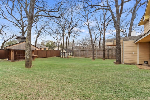 view of yard with a fenced backyard, an outdoor structure, and a storage shed