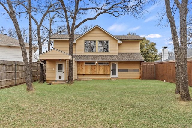 back of property featuring a shingled roof, a lawn, and a fenced backyard