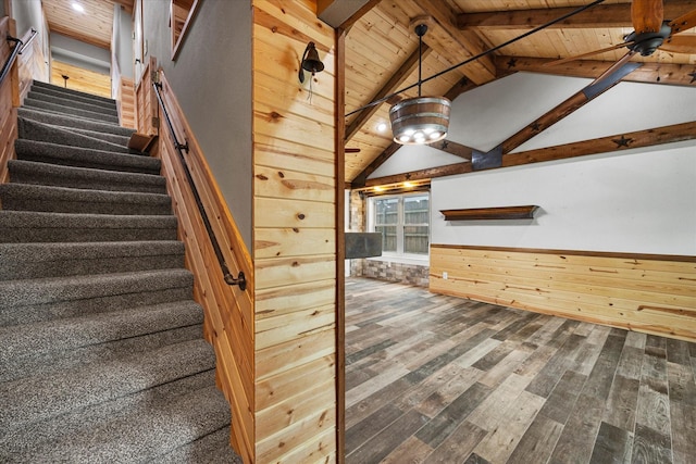 staircase featuring a wainscoted wall, vaulted ceiling with beams, wooden walls, wood finished floors, and wooden ceiling