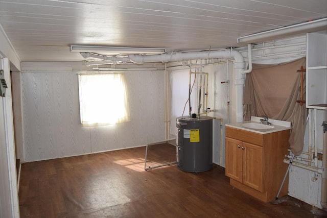 below grade area with dark wood-style floors, electric water heater, and a sink