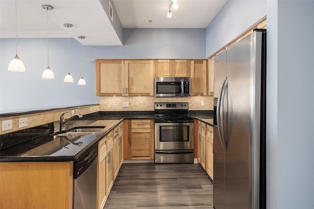 kitchen with appliances with stainless steel finishes, a peninsula, a sink, light brown cabinetry, and backsplash