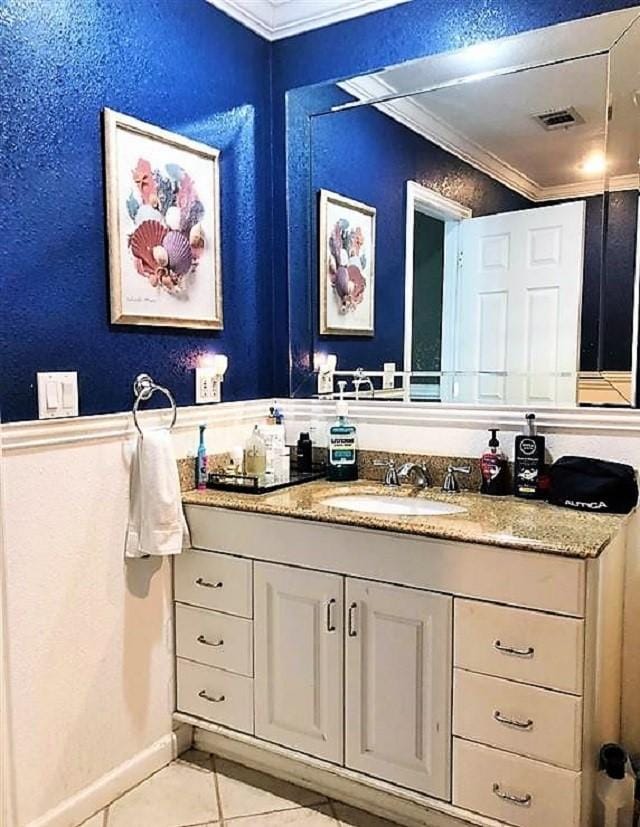 bathroom featuring a textured wall, vanity, visible vents, ornamental molding, and tile patterned floors