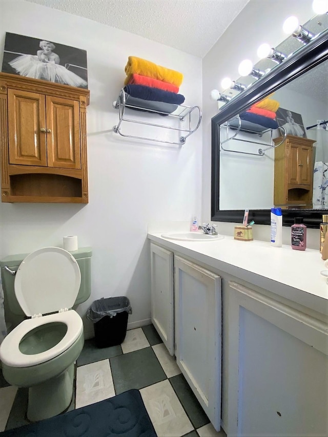 bathroom with a textured ceiling, toilet, vanity, and tile patterned floors