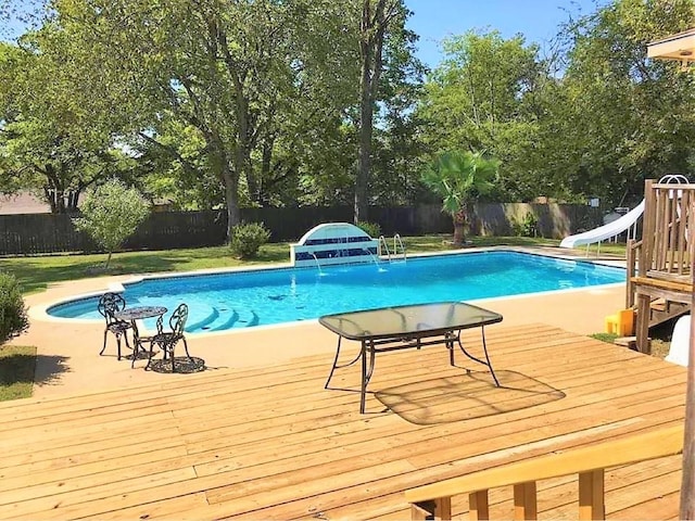 view of pool featuring a wooden deck, a water slide, a fenced backyard, and a fenced in pool